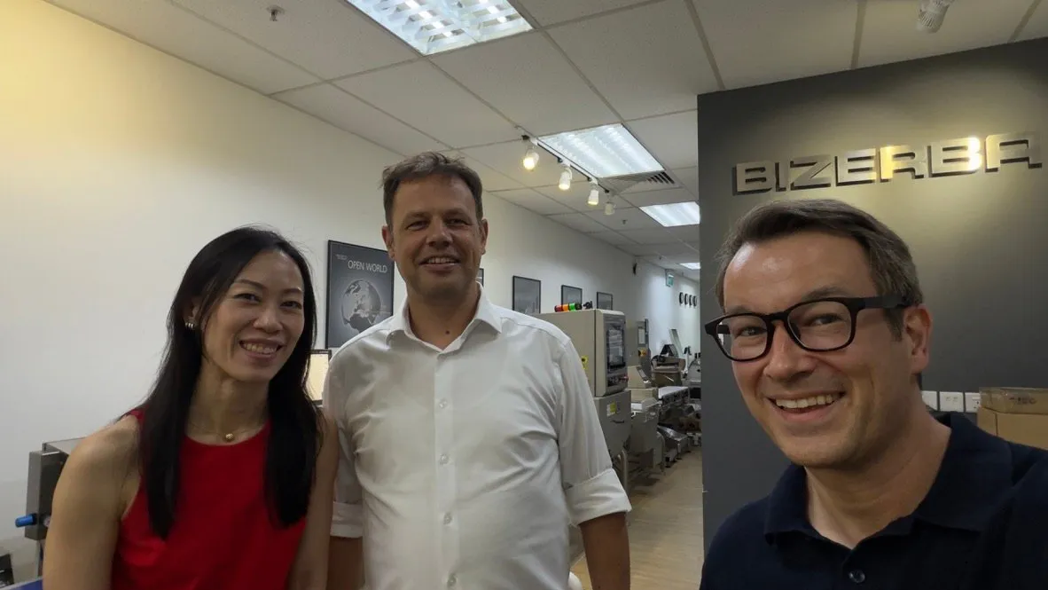 The Meridium team with their host in the Bizerba showroom at the German Centre, with the Bizerba logo on the wall and machines on display behind them