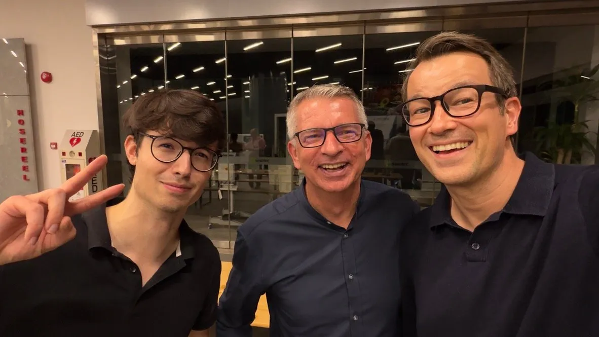 The Meridium team with two guests in the lobby of the German Centre, with a glass-walled office behind them