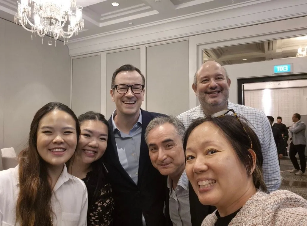 Guests at the lunch smiling together for a group selfie in the ballroom